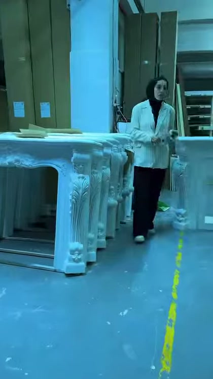 Sunucu üretim alanındaki işlemeli şömine çeşitlerinin önünde duruyor