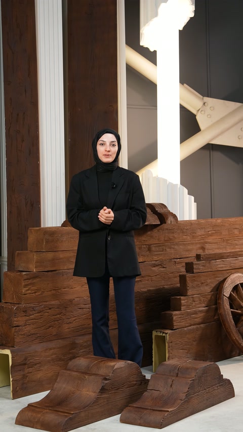 Sunucu, sütunlu alanda sergilenen poliüretan ürünleri tanıtıyor