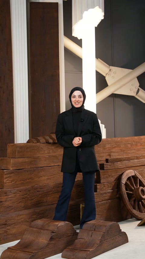 Sunucu, rustik dekoratif parçaların bulunduğu standın önünde duruyor