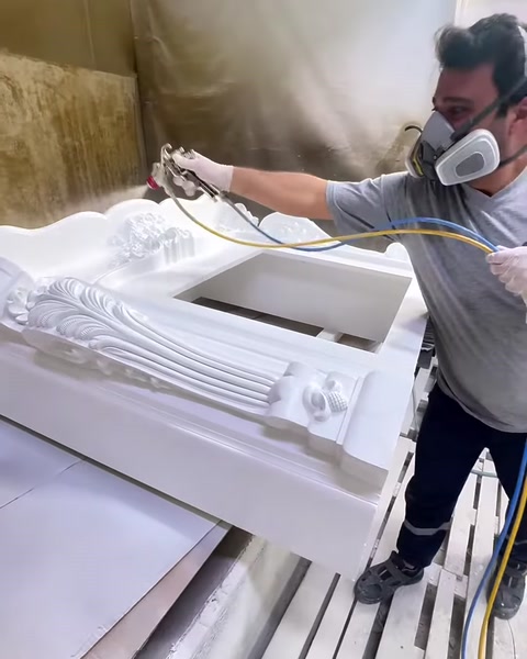 Usta geniş şömine çerçevesini püskürtme tabancasıyla eşit biçimde kaplıyor.