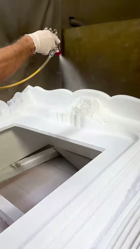 Püskürtme tabancası şöminenin dalgalı üst bölümüne boya uyguluyor