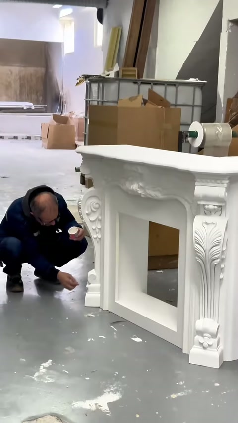 Çalışan bitmiş şöminenin alt köşe detaylarını çömelerek kontrol ediyor