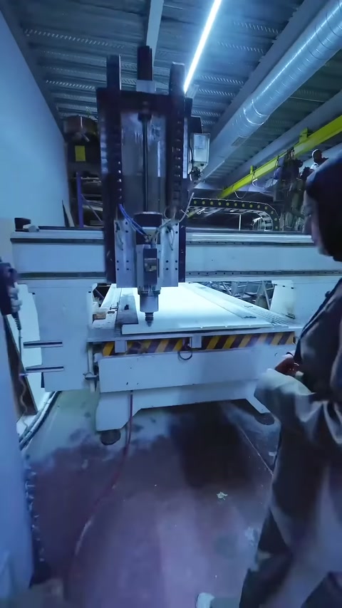CNC makinesi panel üzerinde ilerlerken operatör arkadan gözlemliyor