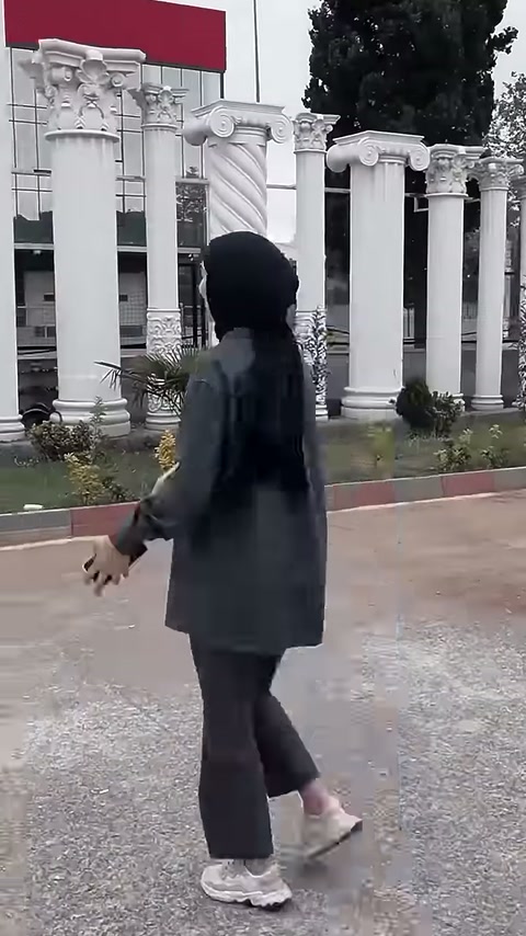 Açık alanda duran beyaz düz sütunlar sunucunun arkasında görülüyor.