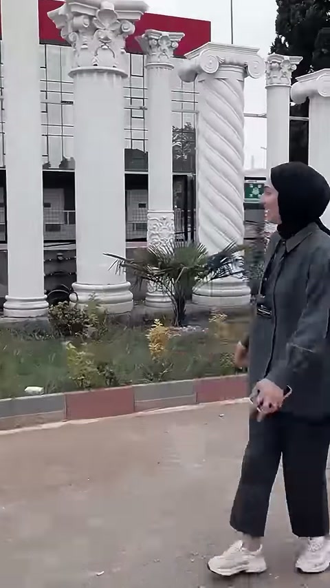 Sunucu, bahçe kenarında sıralanan bezemeli sütunları eliyle işaret ediyor.
