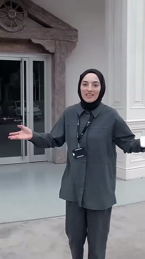 Sunucu, dekoratif sütunlu giriş düzenlemesini kollarını açarak sunuyor.