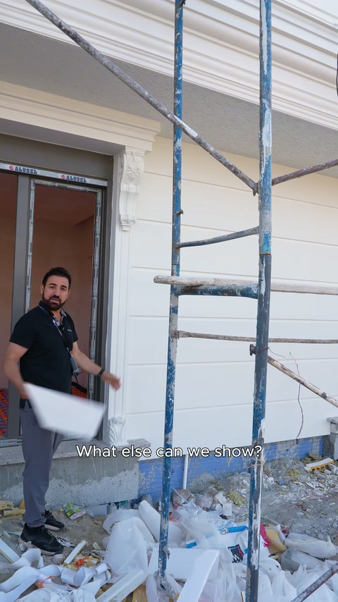İskele önündeki sunucu, tamamlanan pencere çerçevesi yanında konuşuyor.