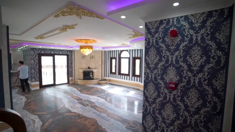 Salonda desenli duvar kaplaması ve ışıklı tavan dekorasyonu bulunuyor
