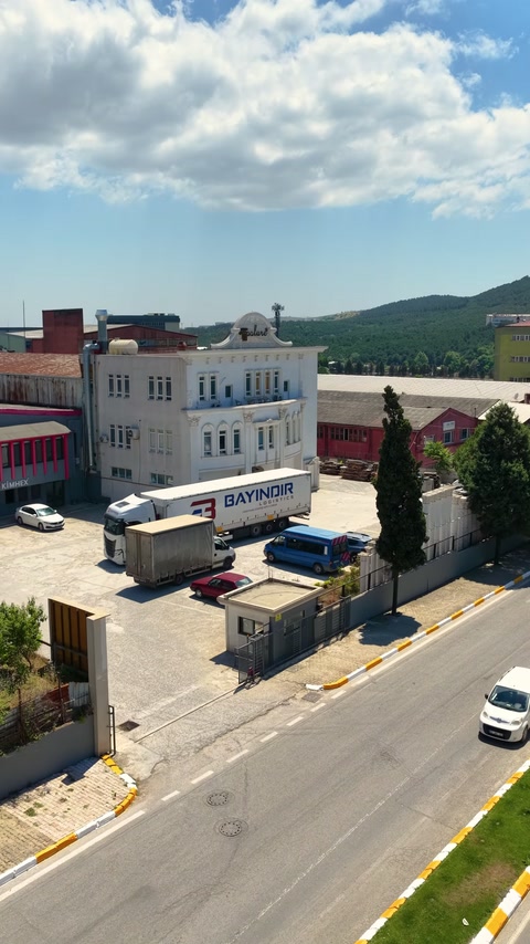 Sevkiyat kamyonu üretim tesisinin ön cephesi boyunca park ediyor