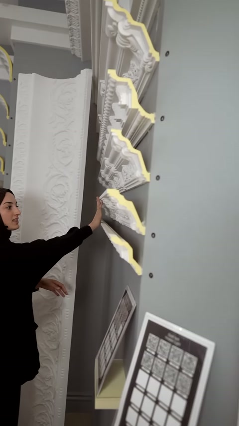 Duvar rafındaki işlemeli kartonpiyer profilleri sunucunun eliyle karşılaştırılıyor.
