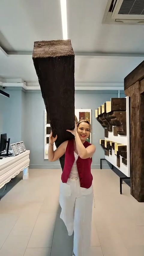 Kadın çalışan, showroom içinde ahşap dokulu poliüretan kirişi omzunda taşıyor.