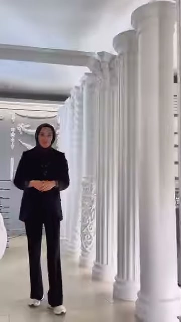 Tanıtıcı, farklı sütun tiplerinin sıralandığı showroom koridorunda kameraya konuşuyor.
