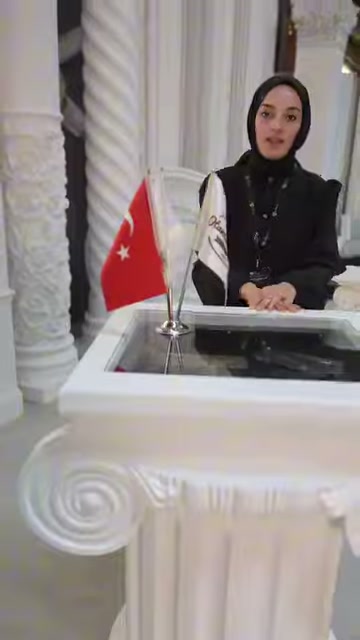 Sunucu, klasik sütunlarla çevrili dekoratif sehpanın arkasında duruyor