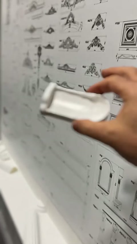 Kemer üstü dekor parçası ürün çizimlerinin önünde elde tutuluyor