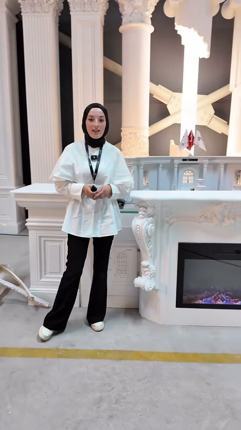 Sunucu sütunlarla çevrili showroomda dekoratif şömineyi tanıtıyor