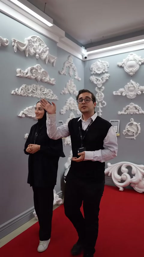 Sergi görevlileri gri duvara monte beyaz süsleri tanıtıyor