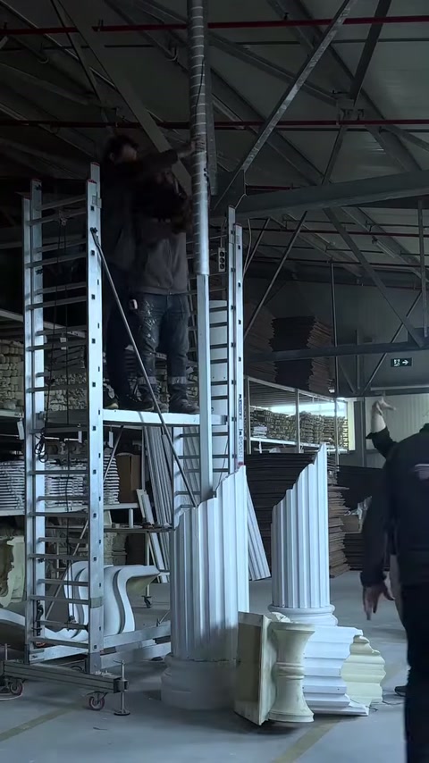 İki usta yüksek sütun gövdesini atölye zemininde sabitliyor.